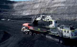 Excavator loading coal into truck in open air mine.