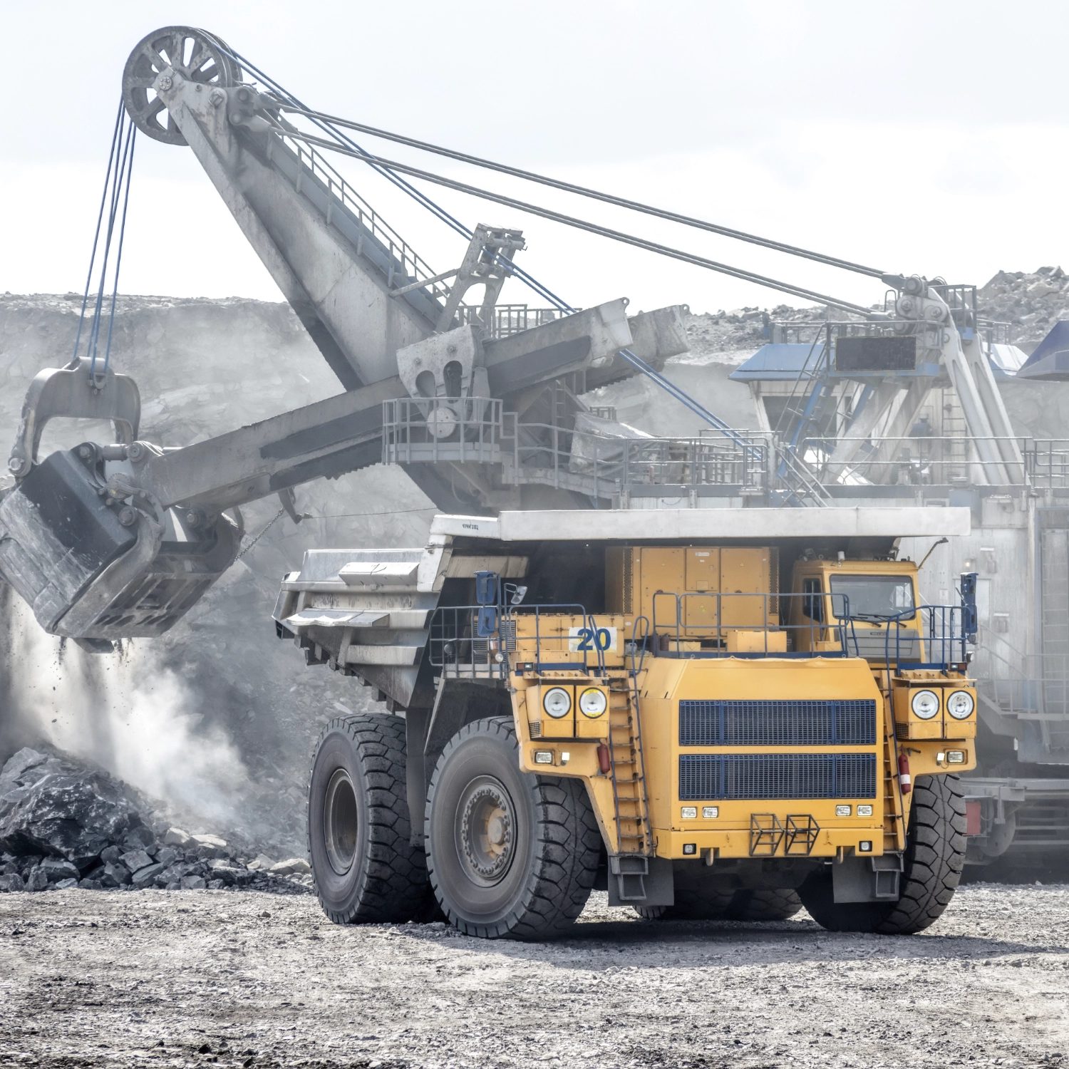 Big truck on excavation site with heavy mining equipment in the background.
