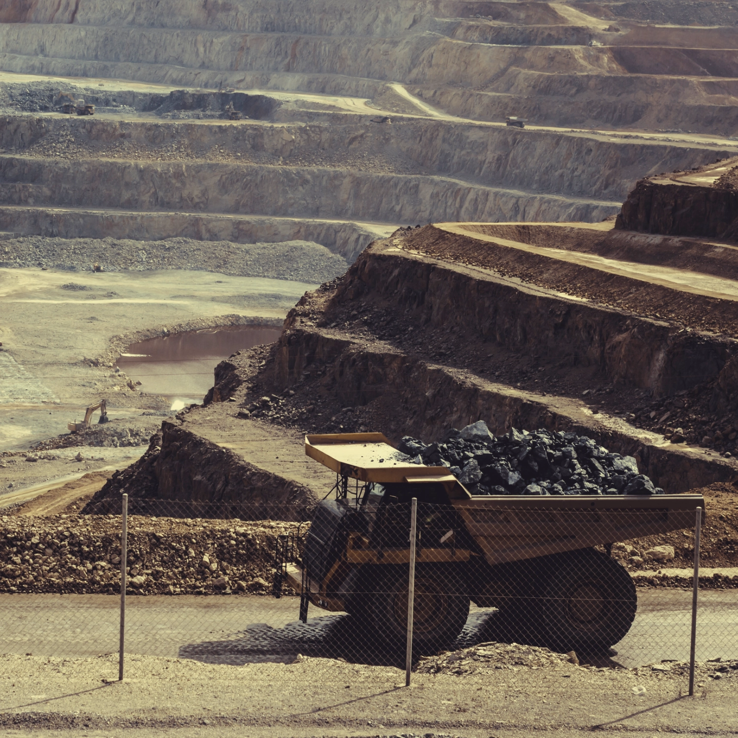 Big truck hauling minerals in big excavation site.