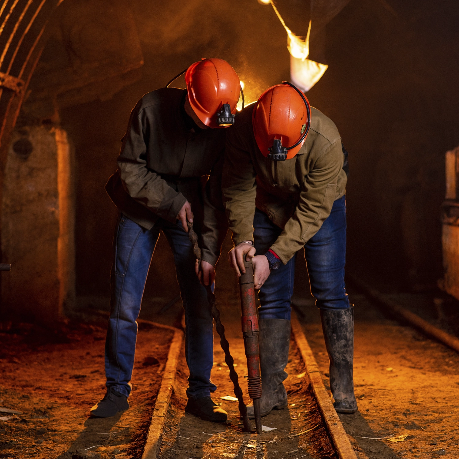 Two miners repairing underground rail.